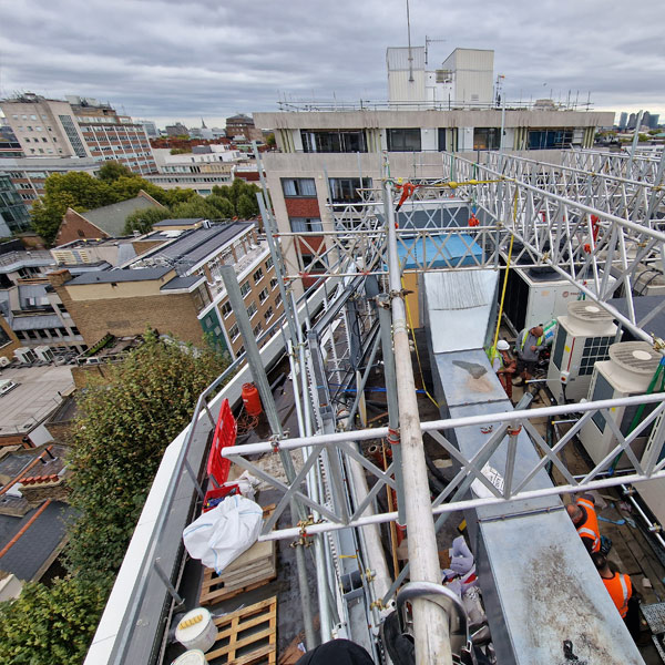 Roofing contractor working beneath temporarily raised HVAC plant